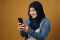 Portrait of happy successful muslim Asian woman smiling while reading message text good news on her smart phone, over yellow Royalty Free Stock Photo