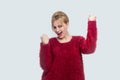 Portrait of happy successful rejoicing beautiful young blond woman in red blouse standing, and celebrating her victory with Royalty Free Stock Photo