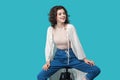 Portrait of happy successful satisfied beautiful young brunette woman in casual style sitting on chair, toothy smiling and looking Royalty Free Stock Photo