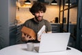 Portrait of happy surprised young curly man opening gift box with present during video call on laptop computer sitting Royalty Free Stock Photo