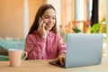 Portrait of happy teen girl talking on cellphone and typing on laptop keyboard, sitting at desk, talking with friends Royalty Free Stock Photo