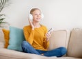 Portrait of happy teen girl wearing wireless headphones listening music on smartphone Royalty Free Stock Photo