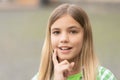 Portrait of happy teenage girl smiling with finger on cheek blurry outdoors Royalty Free Stock Photo