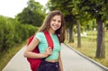 Portrait of happy, smiling teenage school girl with backpack standing in the park Royalty Free Stock Photo