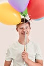Portrait of happy teenaged disabled boy with Down syndrome smiling at camera, holding a bunch of colorful balloons while Royalty Free Stock Photo