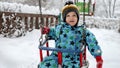 Portrait of happy toddler boy enjoying a winter swing ride in the park, surrounded by snow-covered trees and beautiful winter Royalty Free Stock Photo
