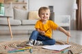 Portrait of happy toddler boy sitting on carpet with colorful pencils and sheet of paper, drawing at home, copy space Royalty Free Stock Photo