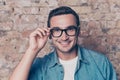 Portrait of happy toothy smart man touching his glasses