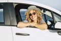 Portrait of happy tourist travel woman smiling at the camera sitting inside a white car looking outside from open window. Summer Royalty Free Stock Photo