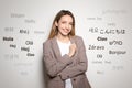 Portrait of happy translator and greeting words in different foreign languages on white background