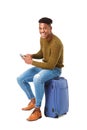 Happy travel man sitting with cellphone on suitcase against isolated white background Royalty Free Stock Photo