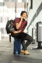 Happy travel man sitting on suitcase at station while talking on cellphone Royalty Free Stock Photo