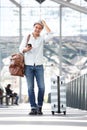 Happy travel man walking in airport terminal with suitcase bag and mobile phone Royalty Free Stock Photo