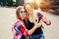 Portrait of a happy two smiling girls making selfie photo on smartphone. urban background. The evening sunset over the Royalty Free Stock Photo