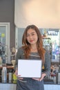 Waitress standing at coffee shop and showing digital tablet with empty display..