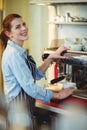 Portrait of happy waitress using espresso machine