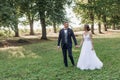 Portrait of happy wedding couple walking on green grass in park in summer. Young attractive woman looking at young man. Royalty Free Stock Photo