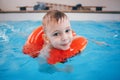 White Caucasian child in swimming pool. Preschool boy training to float with red circle ring in water Royalty Free Stock Photo