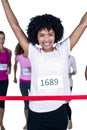 Portrait of happy winner female athlete crossing finish line with arms raised Royalty Free Stock Photo