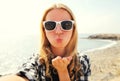 Portrait of happy woman blowing lips sending sweet air kiss stretching hand for taking selfie over sea Royalty Free Stock Photo