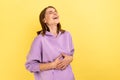 Happy woman with dark hair holding belly, laughing, hearing funny joke or anecdote.