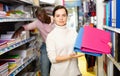 Portrait of happy woman demonstrating pink folder in stationary department of store