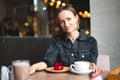 Portrait of a happy woman eating a piece of cake and drinking coffee while sitting at the table in a cafe indoors Royalty Free Stock Photo