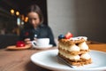 Portrait of a happy woman eating a piece of cake and drinking coffee while sitting at the table in a cafe indoors Royalty Free Stock Photo