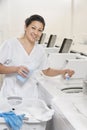 Portrait of a happy woman employee pouring detergent in washer Royalty Free Stock Photo