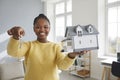 Portrait of a happy woman holding a house model and showing the key to her new home Royalty Free Stock Photo