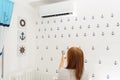 Happy Young Woman Holding Remote Control Relaxing Under The Air Conditioner. Royalty Free Stock Photo