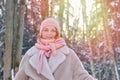 Portrait of a happy woman in a knitted hat, fur coat and scarf, winter forest with trees in the snow Royalty Free Stock Photo