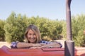 Portrait of happy woman leaning on tractor in olive farm