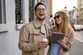 Portrait of happy woman and man walking on the street with coffee, digital tablet and having fun.