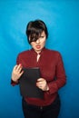 Portrait of happy woman in office, standing with folder on bluw studio background Royalty Free Stock Photo