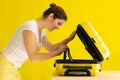 Portrait of a happy woman packs a mini bikini in a suitcase on a yellow background. The girl is going on a trip to the