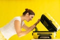 Portrait of a happy woman packs a mini bikini in a suitcase on a yellow background. The girl is going on a trip to the