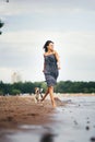 Image of happy woman 20s hugging her dog while walking along the beach Royalty Free Stock Photo