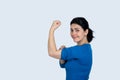 Portrait of a happy woman showing her biceps on gray background. Strong, determined, confident woman pointing to her biceps Royalty Free Stock Photo