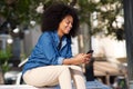 Happy woman sitting outside with mobile phone Royalty Free Stock Photo
