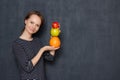 Portrait of happy woman smiling and holding colorful stack of fruits