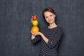 Portrait of happy woman smiling and holding colorful stack of fruits