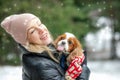 Portrait of happy woman and spaniel dog in winter forest. Woman hold in hands cute little spaniel. Walking in snowfall. Royalty Free Stock Photo