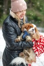 Portrait of happy woman and spaniel dog in winter forest. Woman hold in hands cute spaniel puppy. Walking in snowfall. Royalty Free Stock Photo