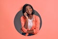 Portrait of happy woman talking on mobile phone in a circle hole in a coral background. Copy space Royalty Free Stock Photo