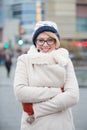 Portrait of happy woman in warm clothing standing arms crossed on city street Royalty Free Stock Photo