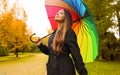 Portrait of a happy woman wearing raincoat under an umbrella breathing in city park on rainy day Royalty Free Stock Photo