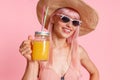 Portrait of happy woman wearing straw hat, swimsuit and sunglasses smiling at camera, drinking tropical juice cocktail Royalty Free Stock Photo