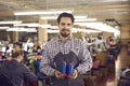 Portrait of happy young worker standing in sewing workshop and holding thread bobbins Royalty Free Stock Photo