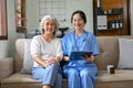 Portrait of a happy 60-year-old elderly woman and a female doctor sitting on the sofa Royalty Free Stock Photo